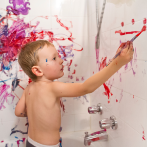  Un niño pintando en la ducha, usando los azulejos como lienzo.