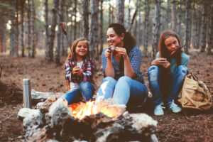 Familia disfrutando de una noche de verano alrededor de una fogata en una acampada